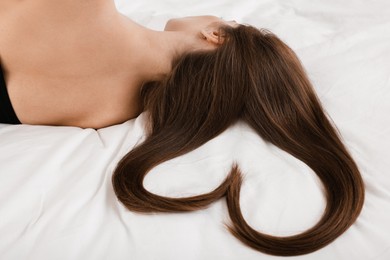 Photo of Young woman with beautiful hair in shape of heart on bed