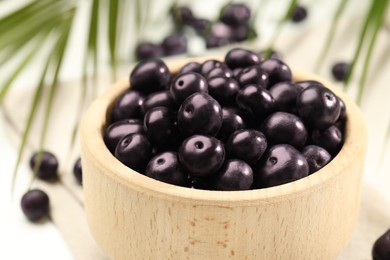 Photo of Ripe acai berries in bowl on table, closeup