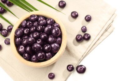 Photo of Ripe acai berries in bowl on white table, flat lay