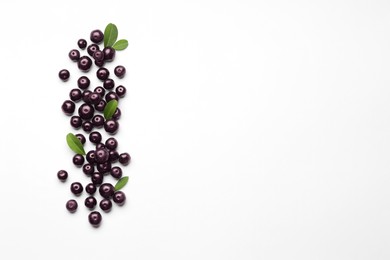 Photo of Ripe acai berries and leaves on white background, flat lay. Space for text