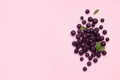 Photo of Ripe acai berries and leaves on pink background, flat lay. Space for text