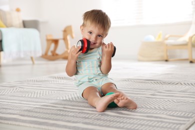 Cute little baby with headphones on floor at home