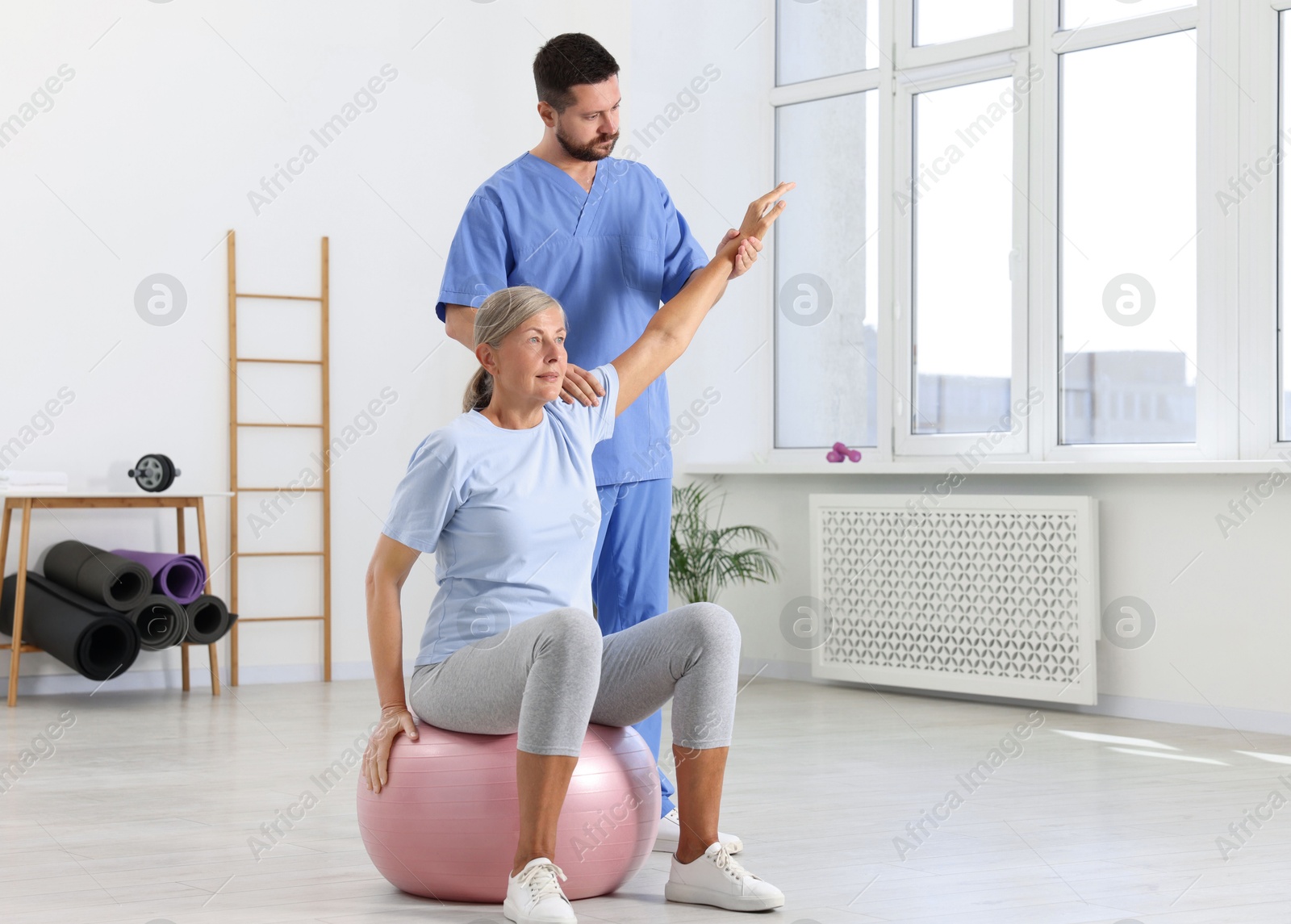 Photo of Physiotherapist working with senior patient in rehabilitation center