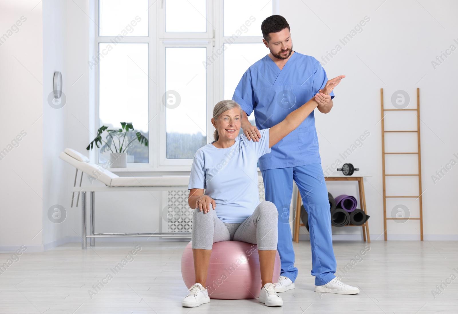 Photo of Physiotherapist working with senior patient in rehabilitation center