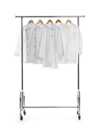 Photo of Different chef's coats on clothing rack against white background