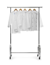 Photo of Different chef's coats on clothing rack against white background