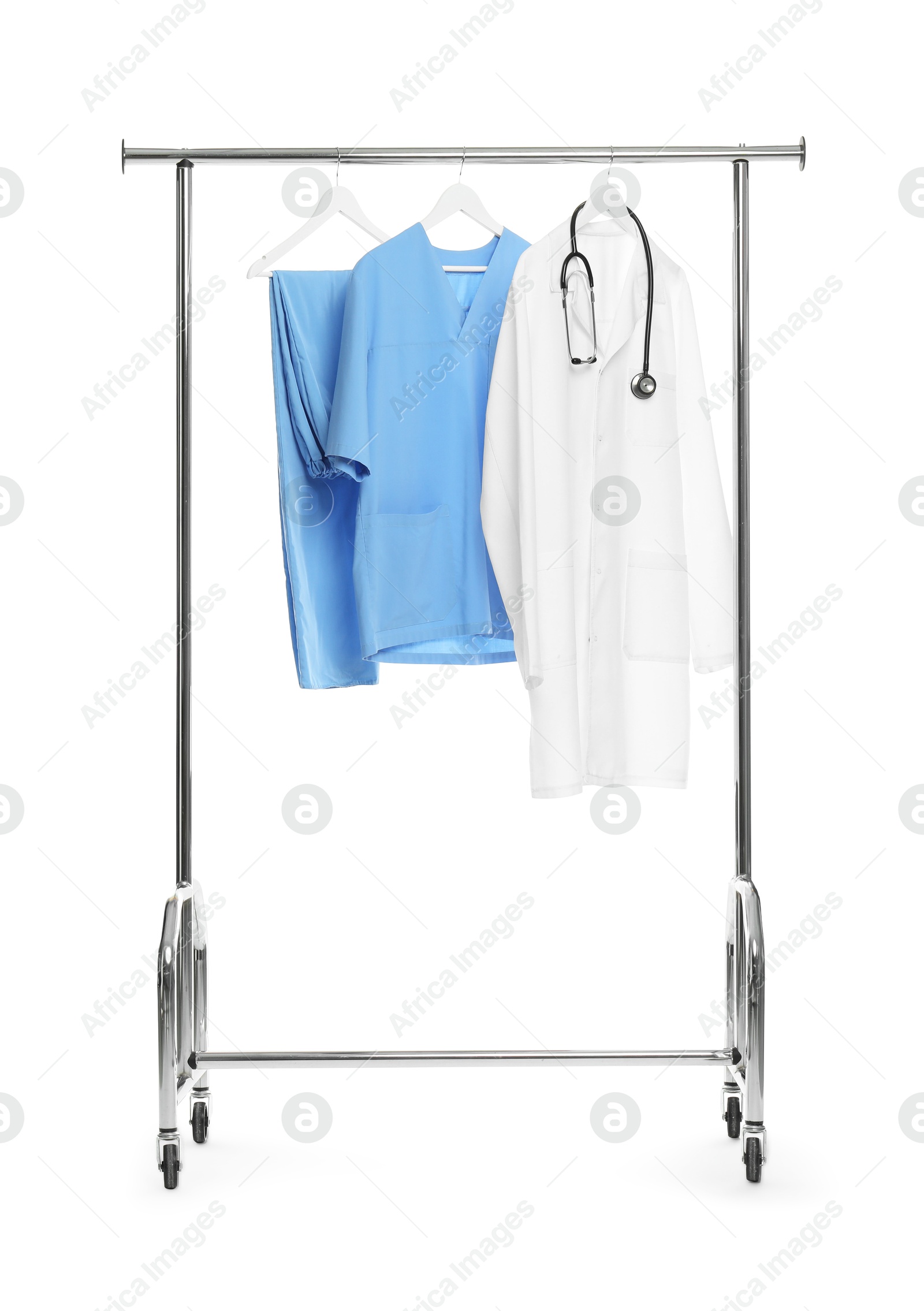 Photo of Different medical workers' uniforms and stethoscope on clothing rack against white background