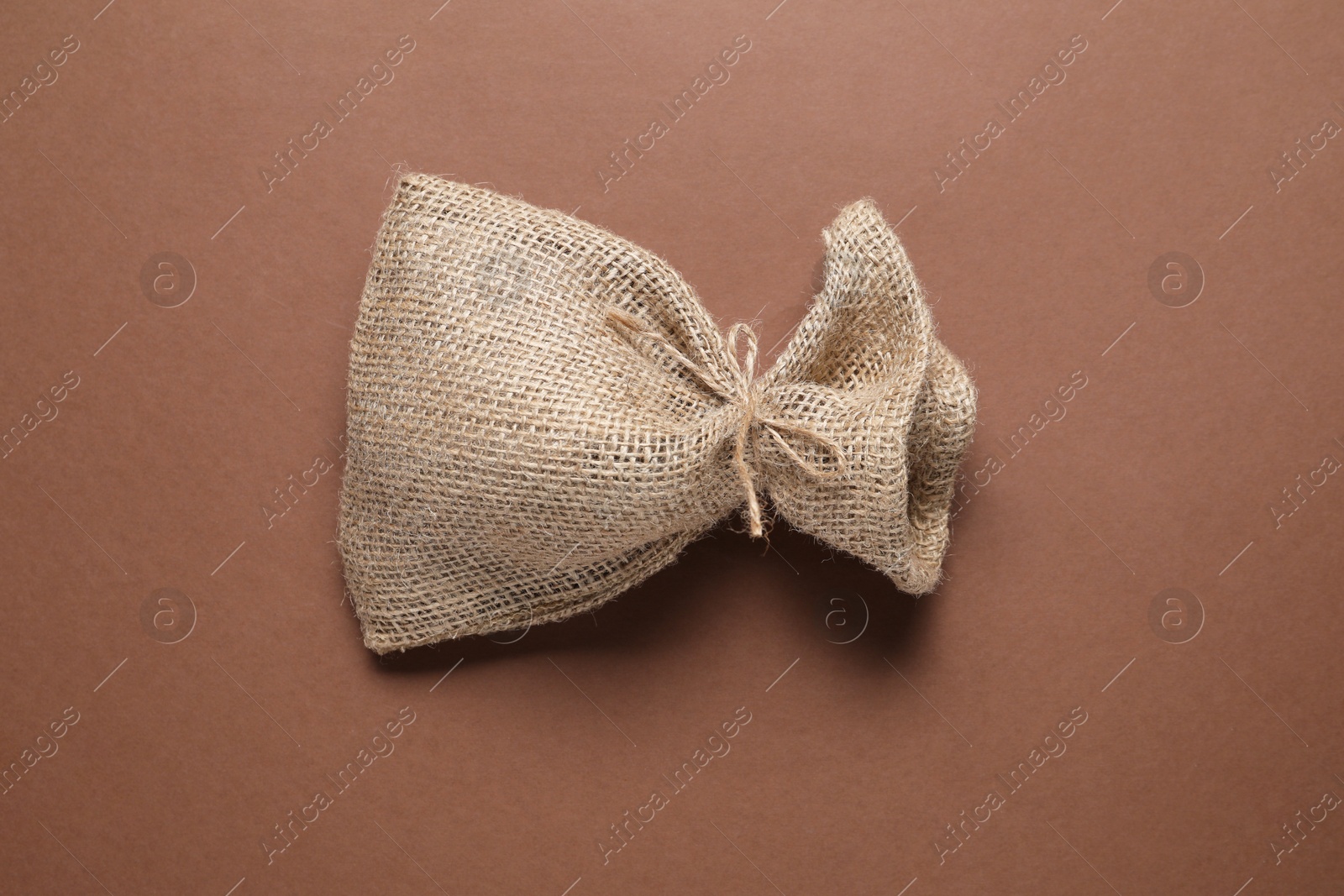 Photo of One burlap sack on brown background, top view