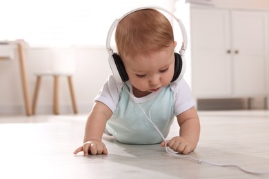 Cute little baby with headphones on floor at home