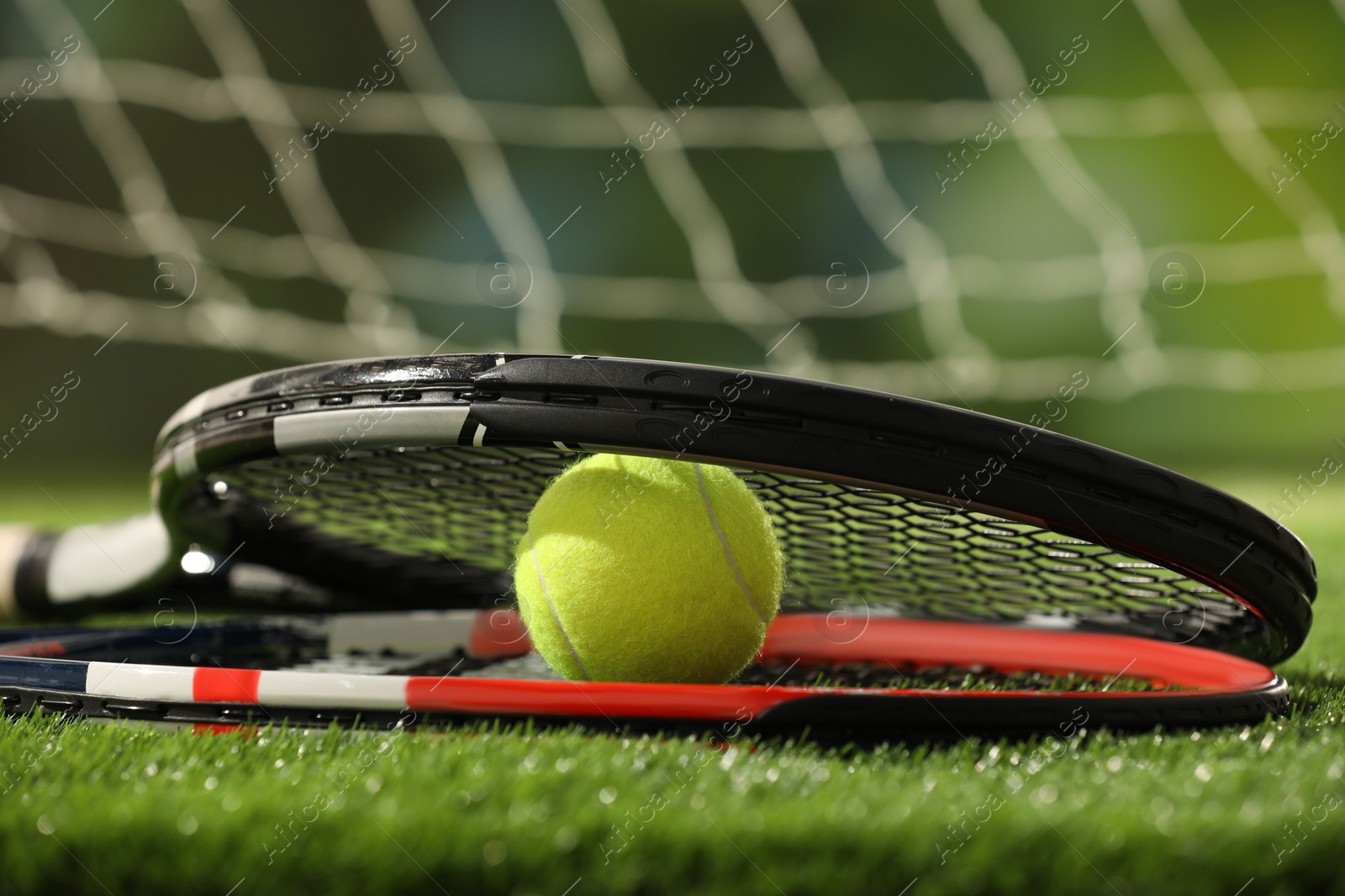 Photo of Tennis racket and ball on green artificial grass, closeup