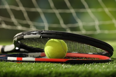 Photo of Tennis racket and ball on green artificial grass, closeup