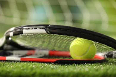 Photo of Tennis racket and ball on green artificial grass, closeup