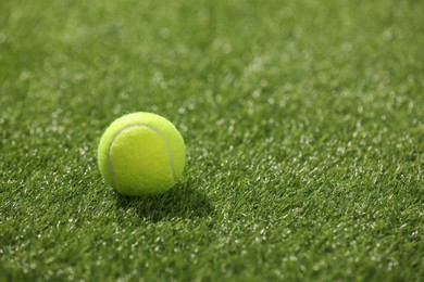 Photo of Tennis ball on green artificial grass, space for text