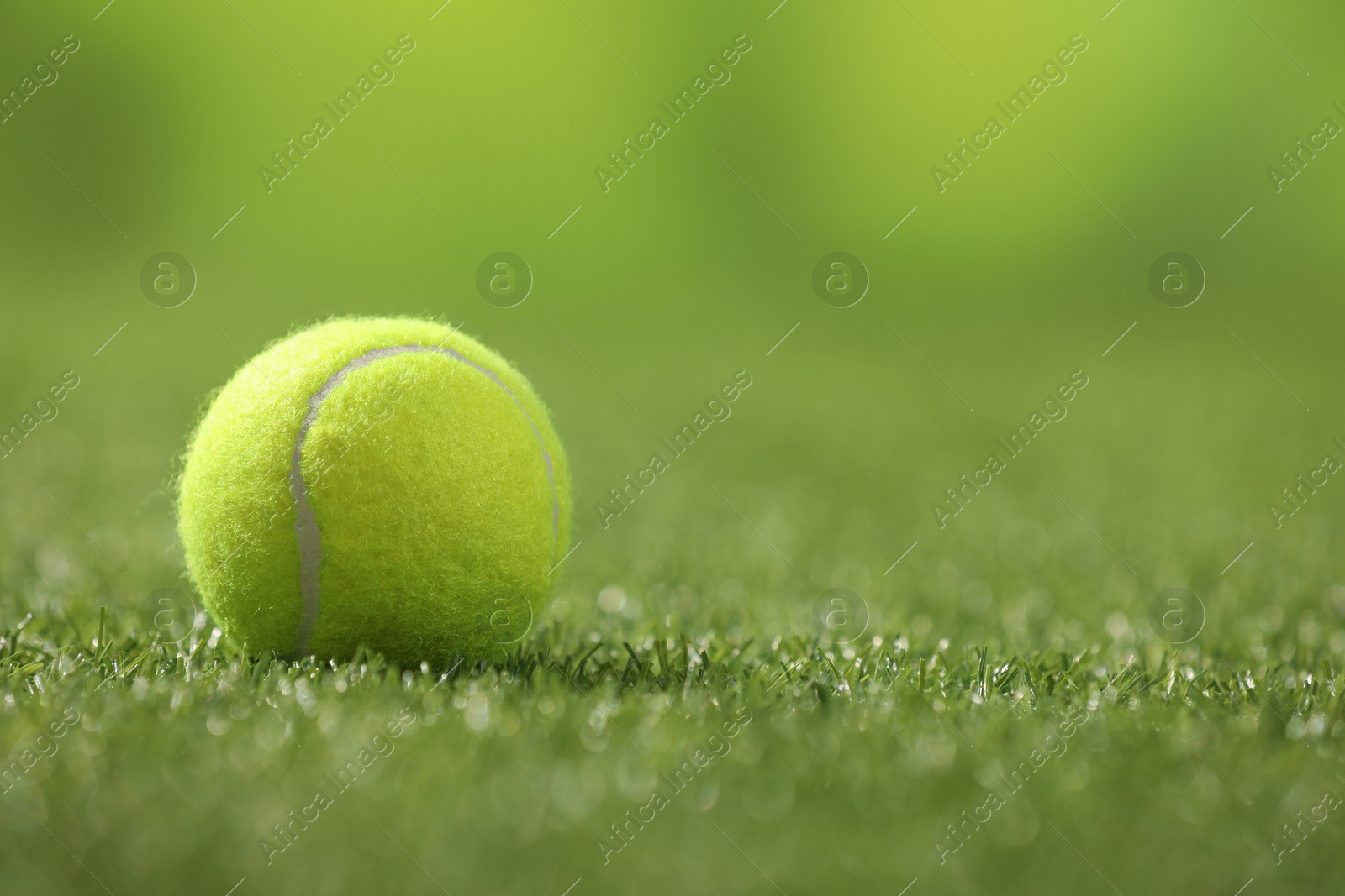 Photo of Tennis ball on green artificial grass, space for text