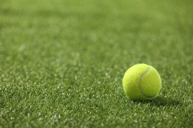 Photo of Tennis ball on green artificial grass, space for text