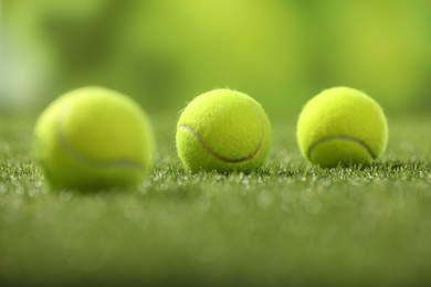 Photo of Many tennis balls on green artificial grass, selective focus