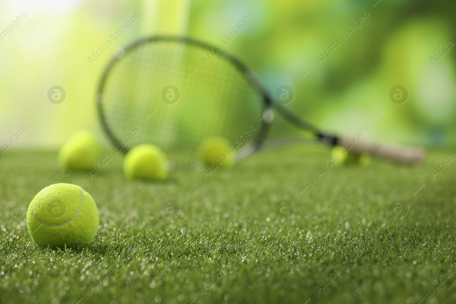 Photo of Tennis racket and balls on green artificial grass, selective focus