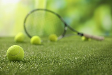 Photo of Tennis racket and balls on green artificial grass, selective focus