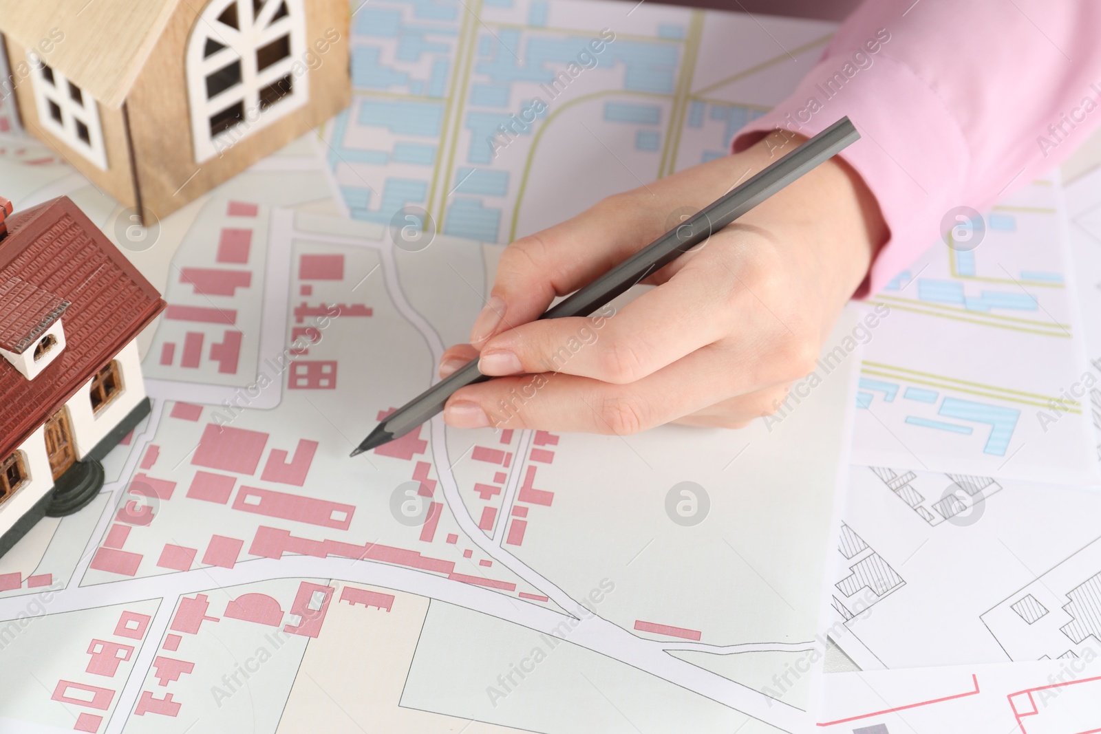 Photo of House hunting. Woman with maps and house figures at table, closeup