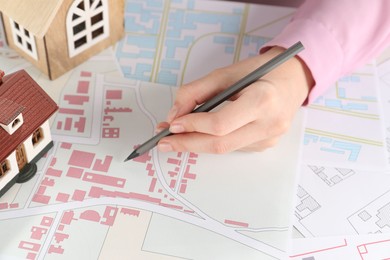 House hunting. Woman with maps and house figures at table, closeup