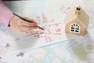 House hunting. Woman with maps and house figure at table, closeup