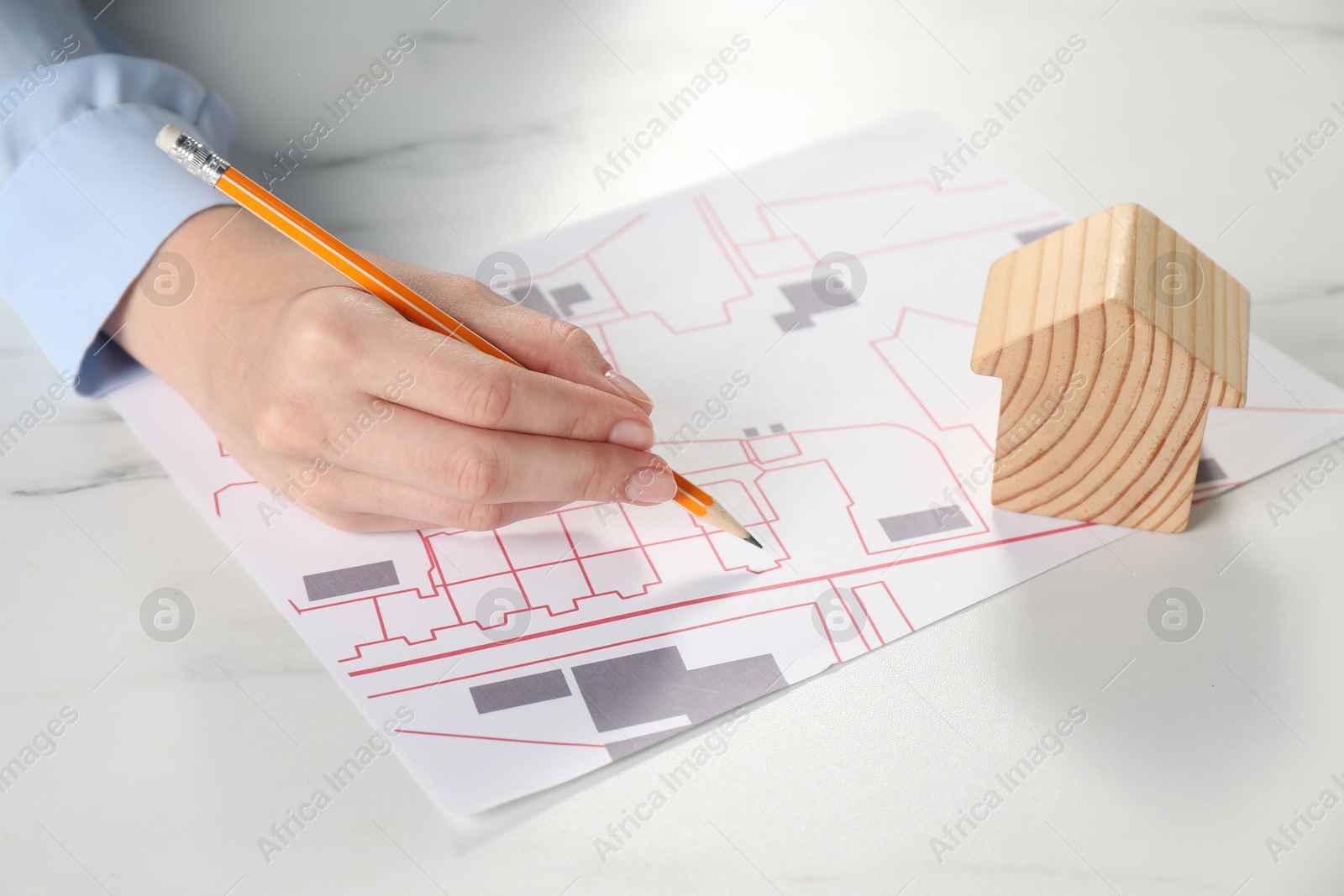 Photo of House hunting. Woman with maps and house figure at white marble table, closeup