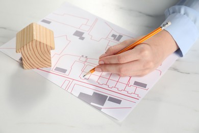 House hunting. Woman with maps and house figure at white marble table, closeup