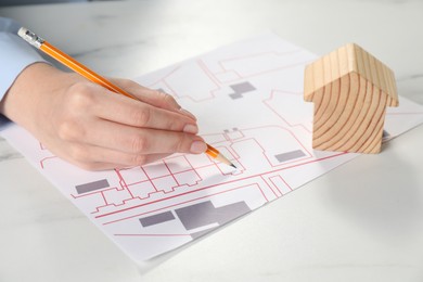 Photo of House hunting. Woman with maps and house figure at white marble table, closeup