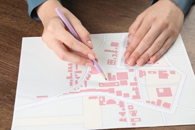 Photo of House hunting. Woman with map at wooden table, closeup