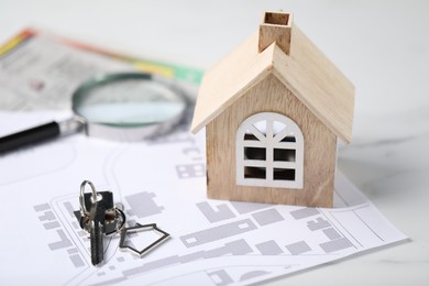 House hunting. Maps, magnifying glass, key and house figure on white marble table