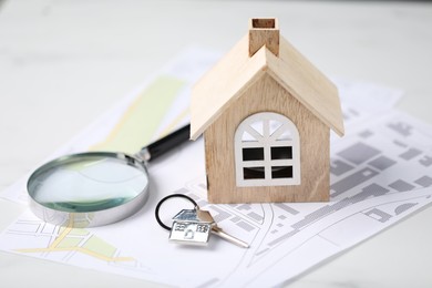 House hunting. Maps, magnifying glass, keys and house figure on white marble table