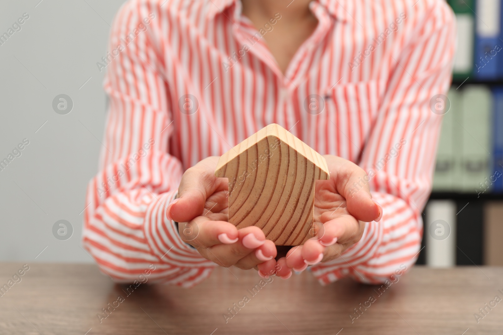 Photo of House hunting. Woman with house figure at wooden table, closeup