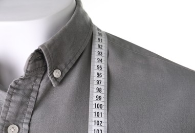 Mannequin with shirt and measuring tape on white background, closeup