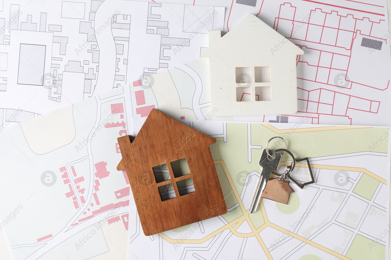 Photo of House hunting. Maps, key and house figures on table, flat lay