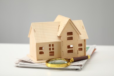 House hunting. Papers, magnifying glass and house figure on white table