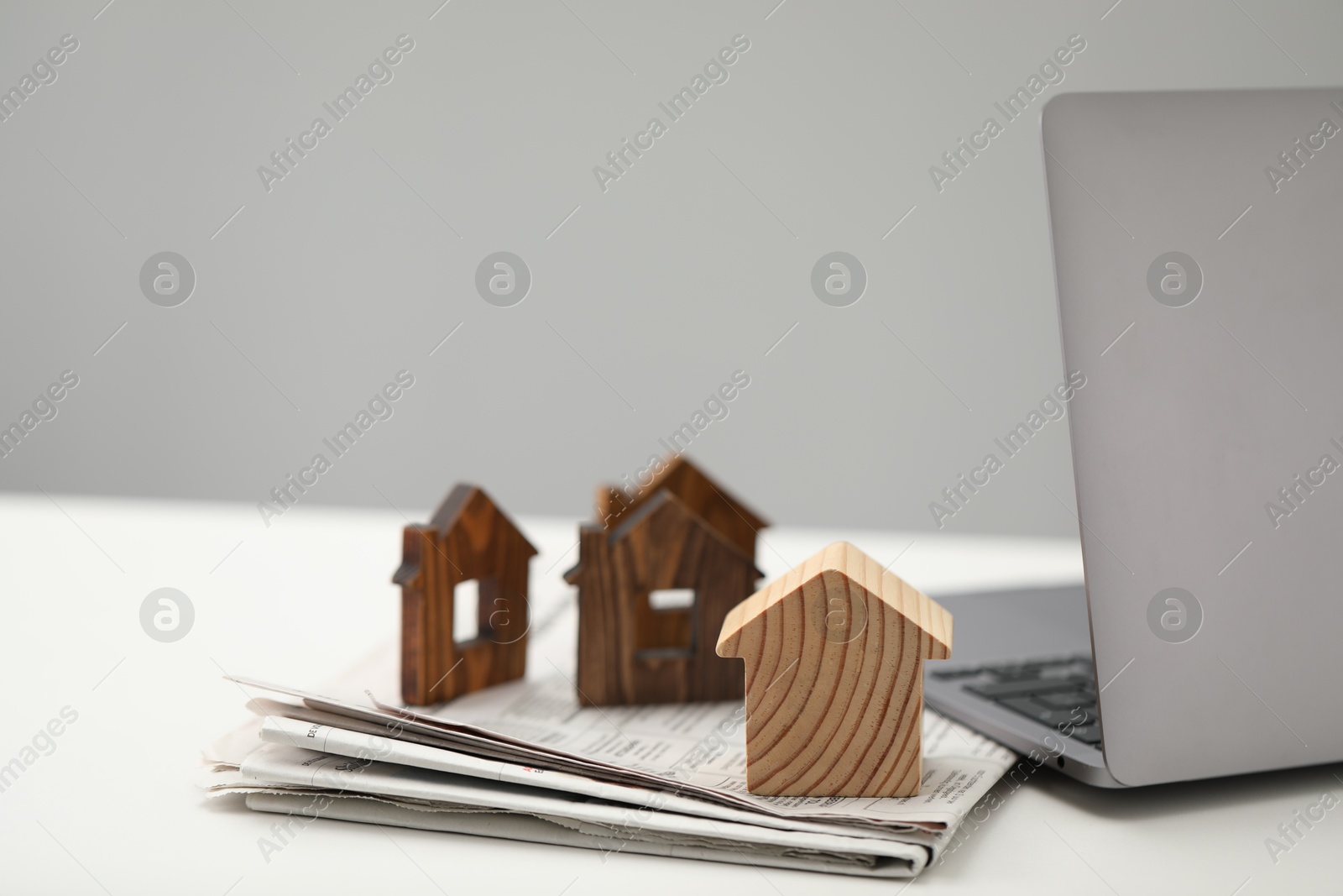 Photo of House hunting. Papers, laptop and house figures on white table