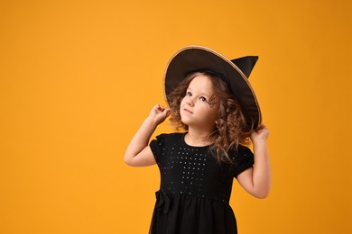 Photo of Cute girl dressed like witch on yellow background. Halloween costume