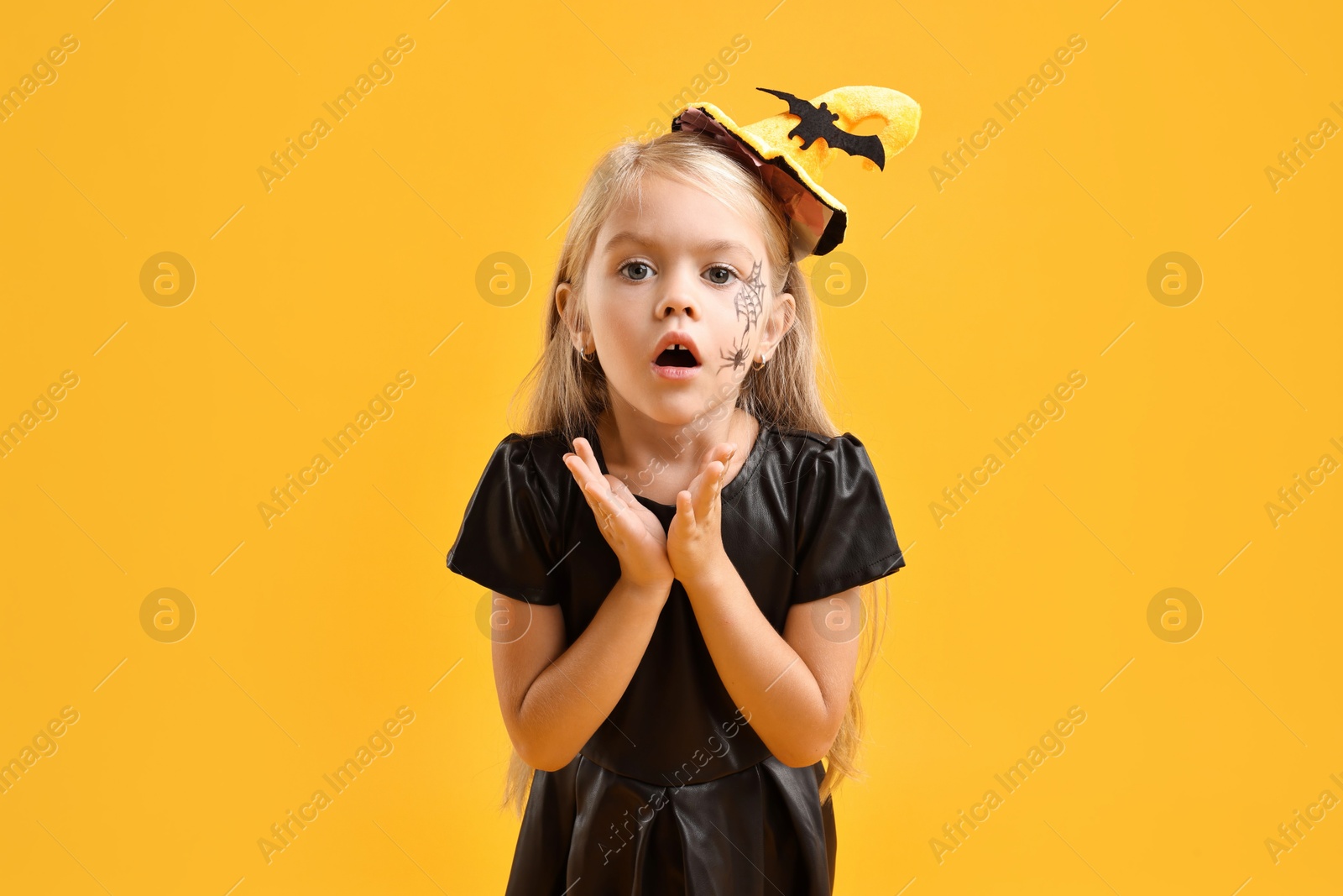 Photo of Cute girl dressed like witch on yellow background. Halloween celebration