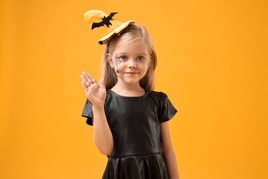 Photo of Cute girl dressed like witch on yellow background. Halloween celebration