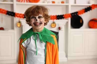 Photo of Funny boy dressed like pumpkin for Halloween celebration in room