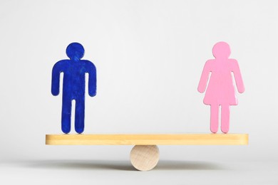 Photo of Gender equality concept. Male and female figures on scales against light background