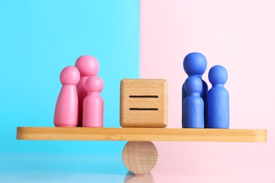 Photo of Gender equality concept. Cube with equals sign between male and female figures on scales against color background