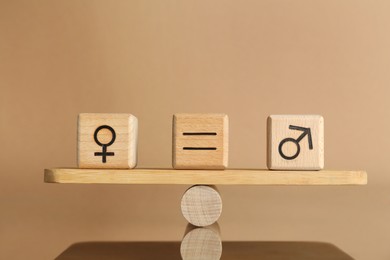 Photo of Gender equality concept. Cubes with male and female symbols on scales against beige background