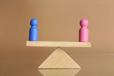 Gender equality concept. Male and female figures on scales against beige background