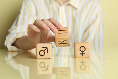 Gender equality concept. Woman with wooden cubes of male and female symbols at table, closeup