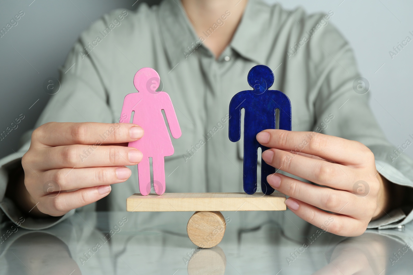 Photo of Gender equality concept. Woman with male and female figures on scales at grey table, closeup