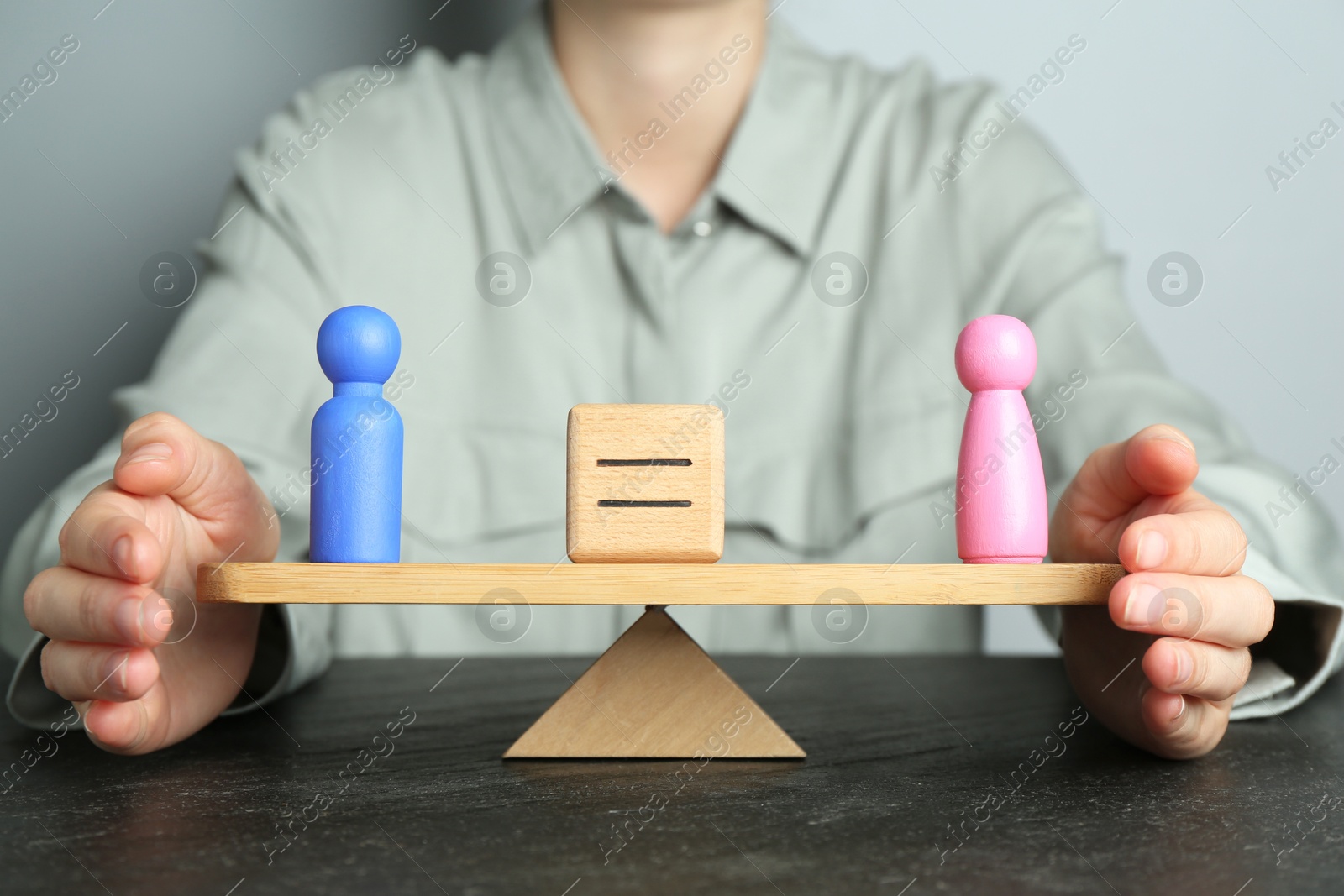 Photo of Gender equality concept. Woman with male and female figures on scales at dark table, closeup