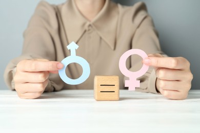 Gender equality concept. Woman with male and female symbols at white table, closeup