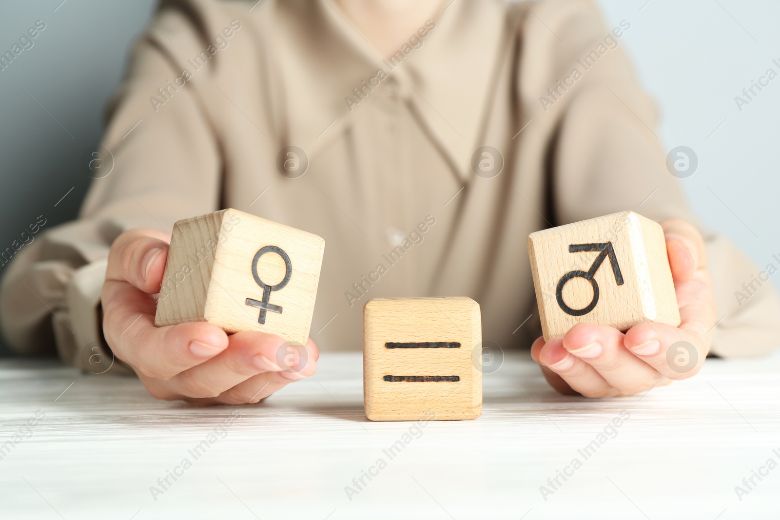 Photo of Gender equality concept. Woman with wooden cubes of male and female symbols at white table, closeup