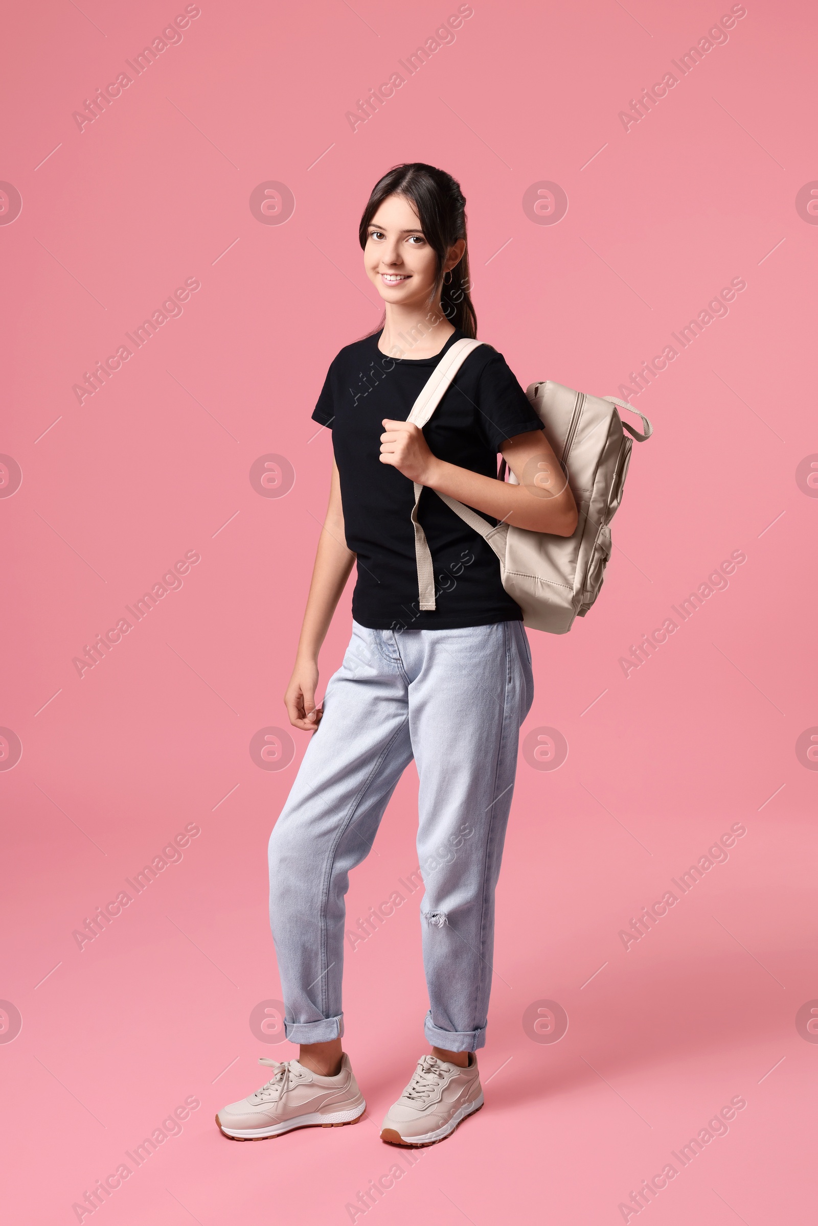 Photo of Cute teenage girl with backpack on pink background